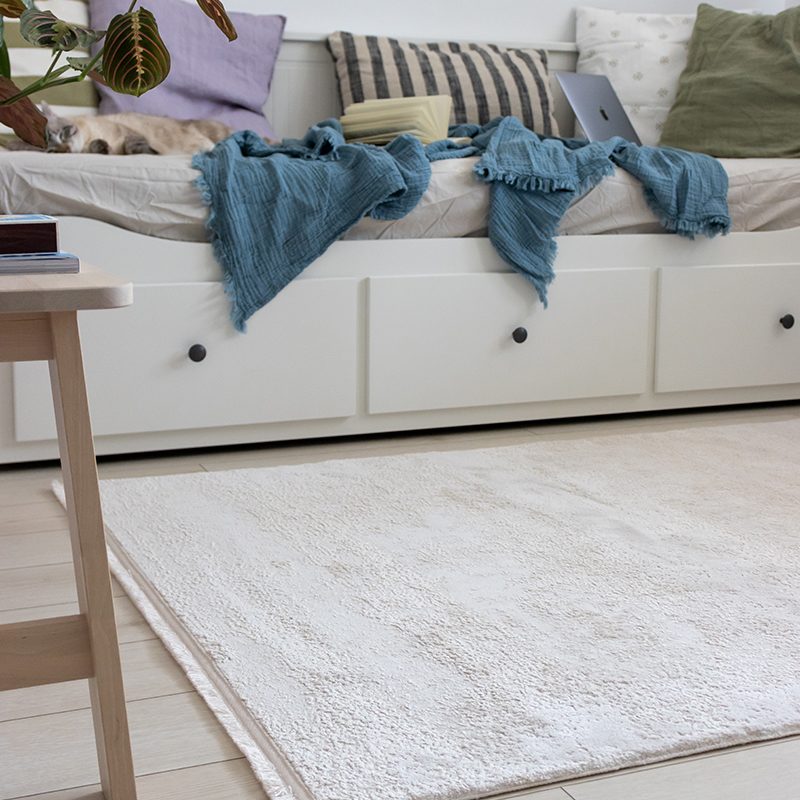 Amenzajarea unui covor crem intr-un dormitor cu un stil minimalist